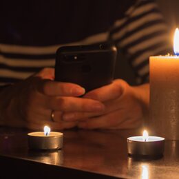 Mobile,Phone,In,Hands,And,Burning,Candles.,Blackout,Due,To