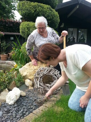 Jugendliche hilft älteren Dame bei der Gartenarbeit